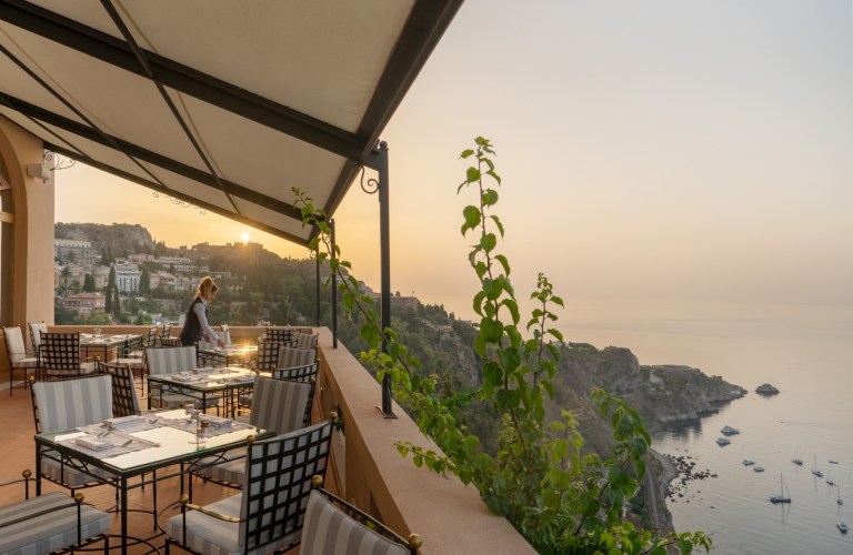 Sunset dining terrace at San Domenico Palace, Sicily’s best luxury hotel and filming location of The White Lotus, offering panoramic views of the Bay of Naxos and the Mediterranean Sea in Taormina.