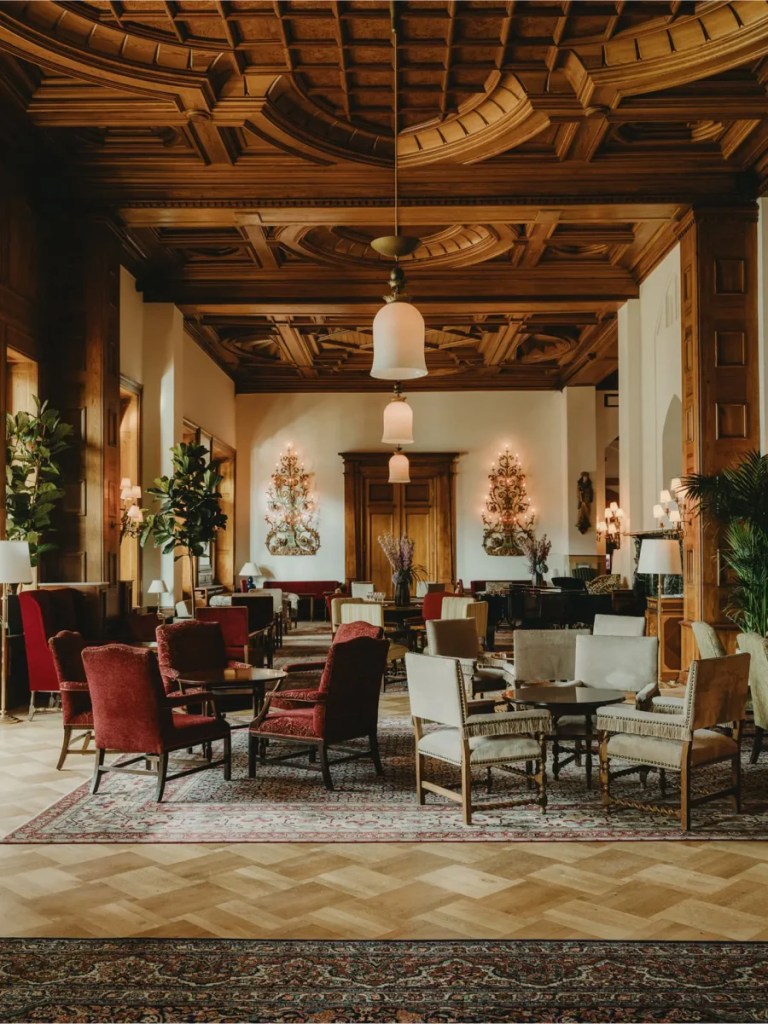Inside the grand lobby of Badrutt’s Palace Hotel, featuring classic interiors, chandeliers, rich fabrics, and the timeless elegance of a historic Grand Hotel.