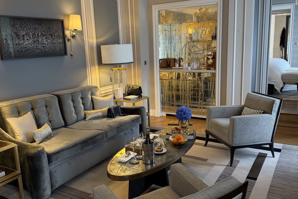 Grand Premier Suite at Hôtel de Crillon, a Rosewood Hotel in Paris, featuring an elegant living area with refined Parisian design, high ceilings, soft neutral tones, curated contemporary furnishings, and large windows allowing natural light to fill the space, highlighting the blend of historic architecture and modern luxury.