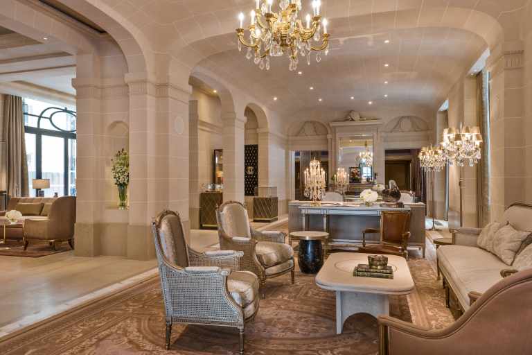 Elegant lobby interior at Hôtel de Crillon in Paris, featuring grand historic architecture, warm ambient lighting, marble floors, refined seating areas, and guests moving through the sophisticated luxury hotel atmosphere overlooking Place de la Concorde.