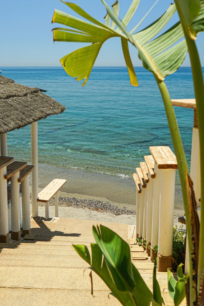Stairway leading to the beach at Viktor's Beach in Marbella with Mediterranean Sea views and tropical plants.