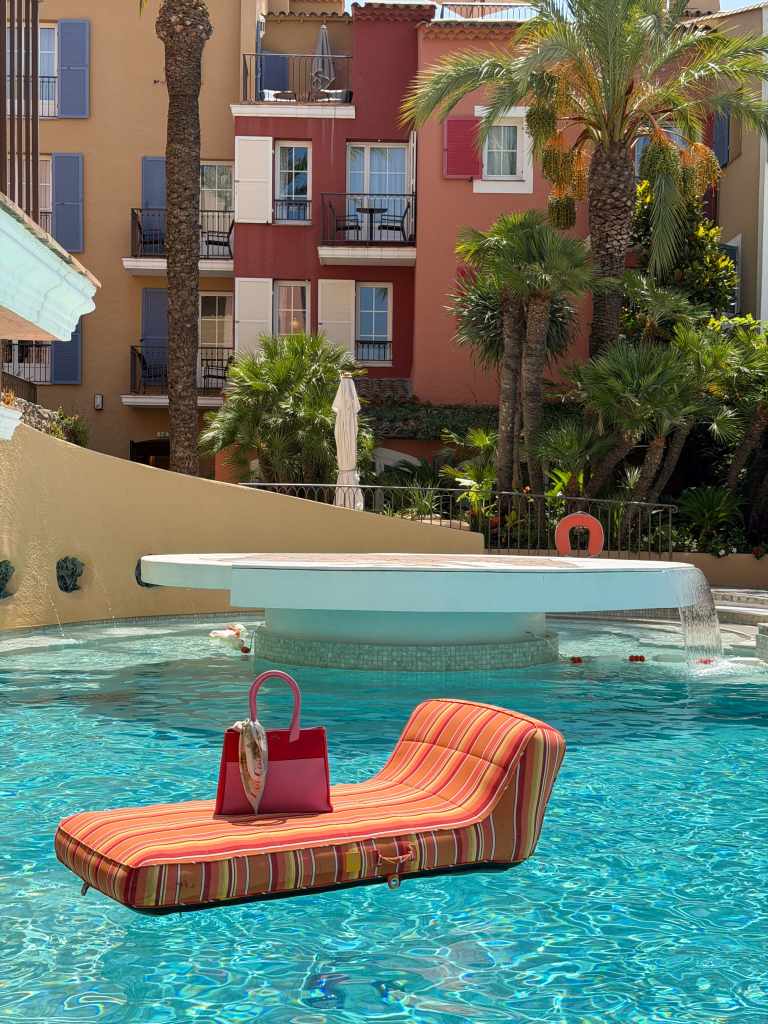 Pink and red LUC8K Tote on a striped sun lounger in the pool at Hôtel Byblos in Saint-Tropez.